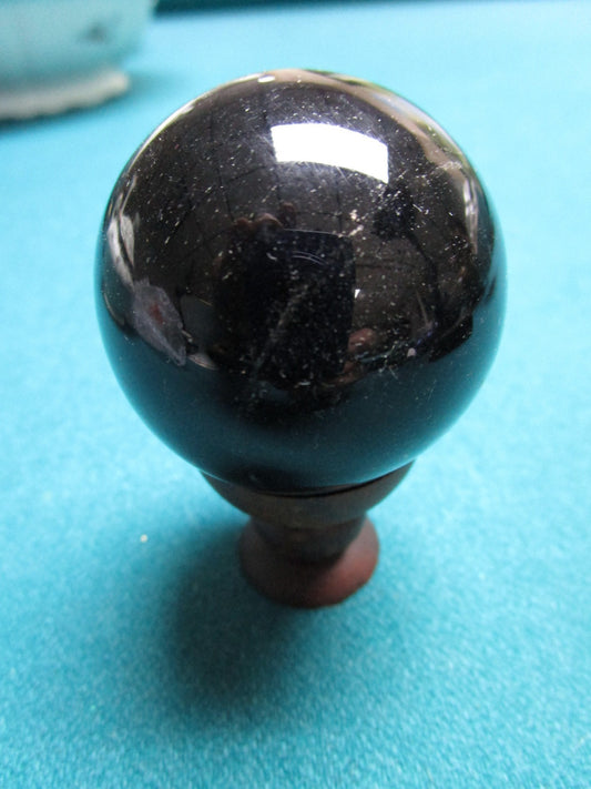 Black Glass studio paperweight on wood  base, 1 1/2" diam ```